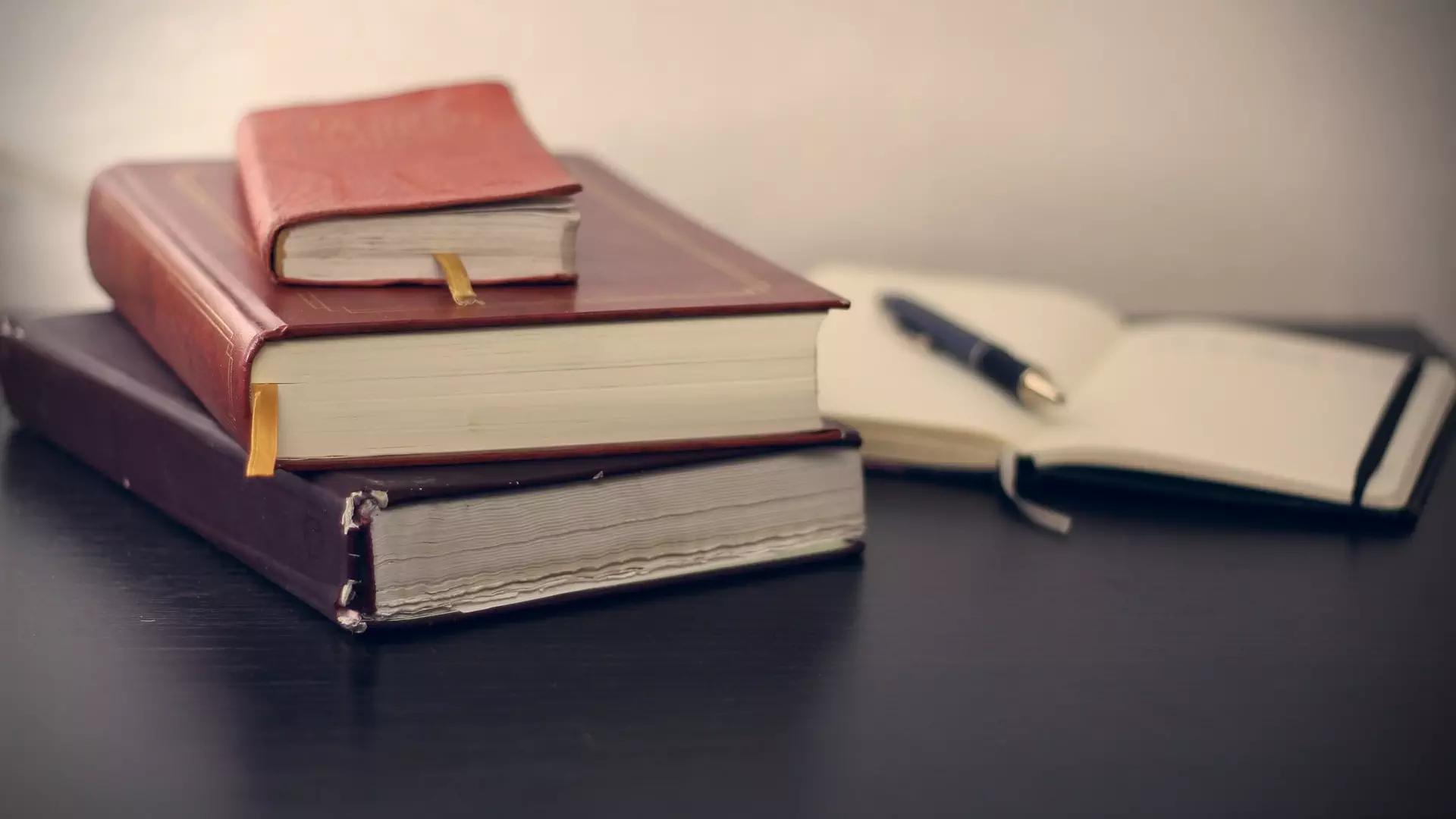 Law books stacked up with pens on top of papers